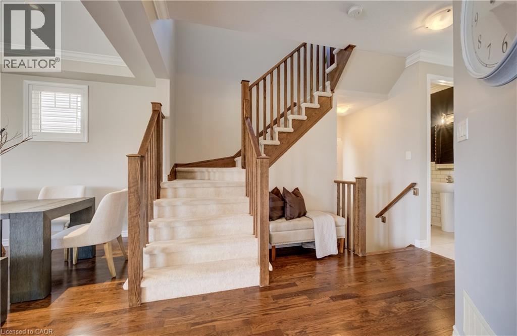 Hardwood-finish flooring extending through the entry, with a carpeted staircase featuring wood newel posts and railings - 19 Shoreacres Drive, Kitchener, ON - Indoor Photo Showing Other Room
