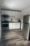 Kitchen featuring white cabinets, dark hardwood / wood-style floors, sink, and appliances with stainless steel finishes -