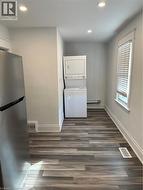 Clothes washing area featuring stacked washer / dryer and dark wood-type flooring -
