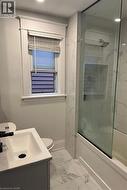 Full bathroom with combined bath / shower with glass door, vanity, and toilet -