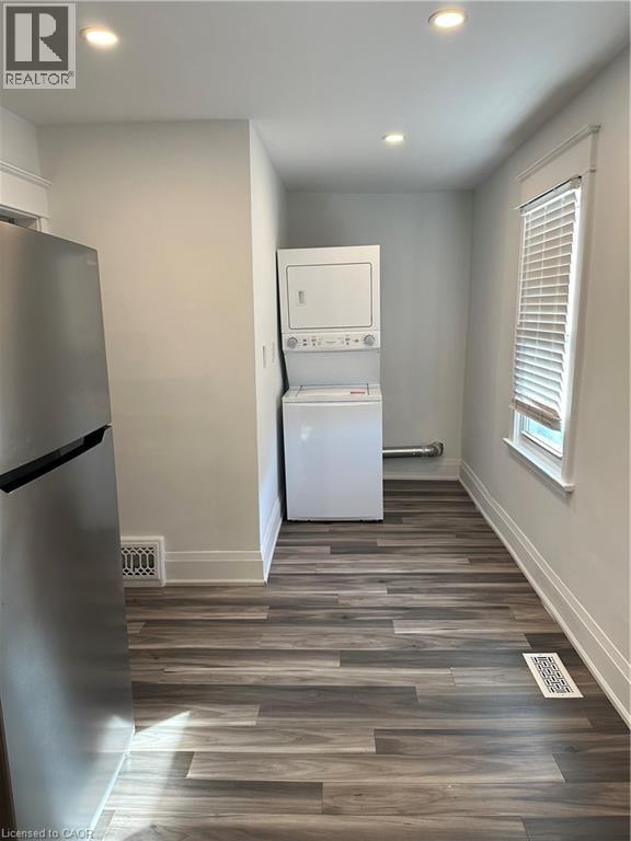 Clothes washing area featuring stacked washer / dryer and dark wood-type flooring - 1090 Cannon Street E, Hamilton, ON - Indoor