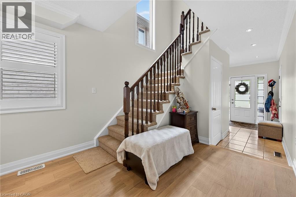Hardwood flooring throughout the main level featuring a carpeted staircase with dark wood banister and white balusters - 4236 Prudham Avenue, Burlington, ON - Indoor Photo Showing Other Room