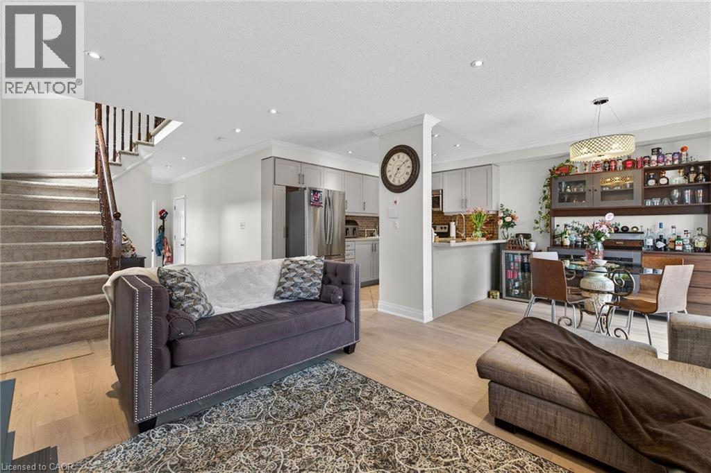 Open-concept living area featuring light wood-finish flooring, recessed lighting, crown molding, and a built-in kitchen island with a breakfast bar - 4236 Prudham Avenue, Burlington, ON - Indoor Photo Showing Living Room