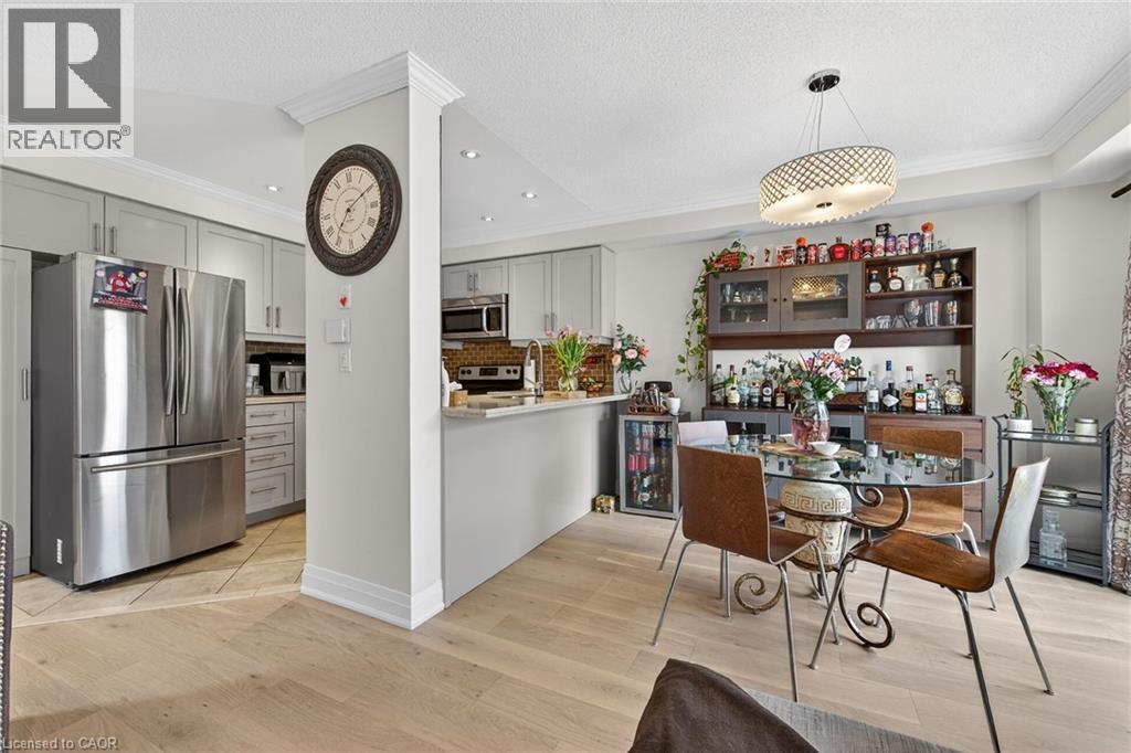 Open-concept dining area featuring a contemporary chandelier and light wood-finish flooring - 4236 Prudham Avenue, Burlington, ON - Indoor