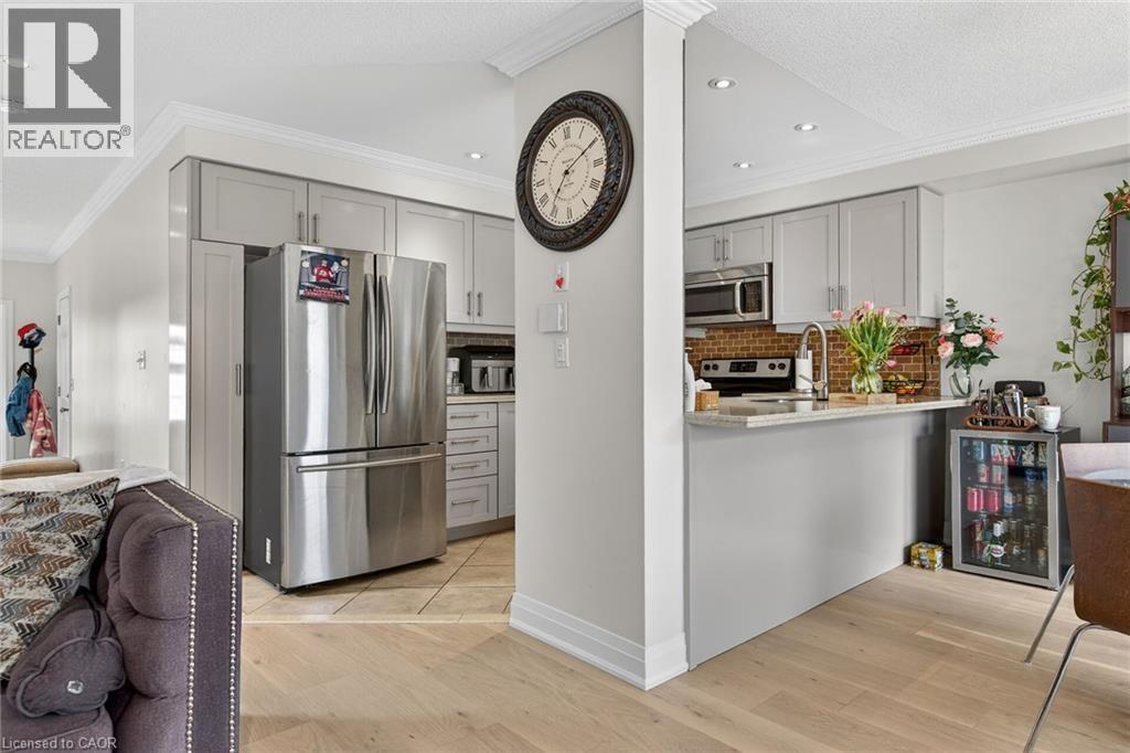 Kitchen featuring light gray cabinetry with brushed nickel hardware, stainless steel appliances, and a brick-patterned backsplash - 4236 Prudham Avenue, Burlington, ON - Indoor Photo Showing Kitchen