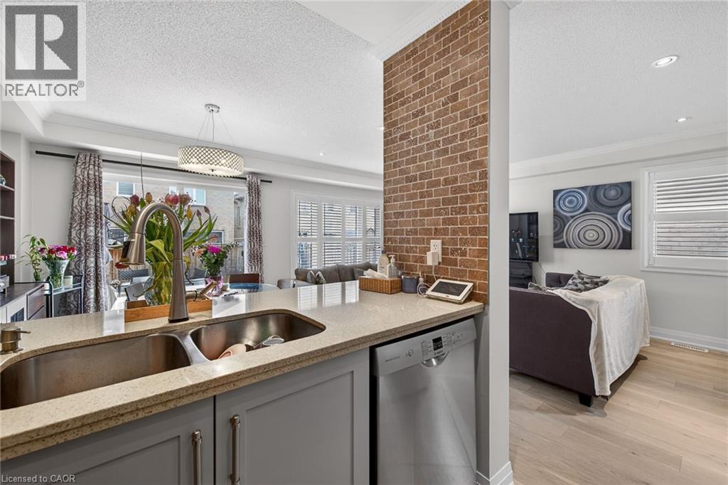 Kitchen island featuring a double basin stainless steel sink with a gooseneck faucet, light granite-style countertop, and integrated dishwasher - 4236 Prudham Avenue, Burlington, ON - Indoor Photo Showing Kitchen With Double Sink