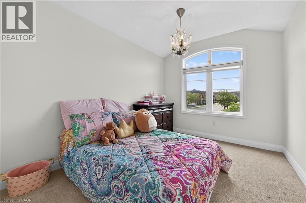 Vaulted ceiling room featuring an arched top window, a crystal chandelier, light neutral-toned walls, and carpet flooring - 4236 Prudham Avenue, Burlington, ON - Indoor Photo Showing Bedroom