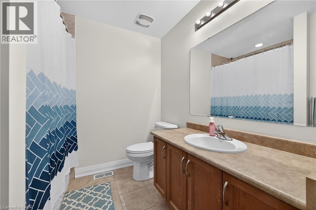 Bathroom featuring a spacious vanity with integrated sink, wood-finish cabinetry, and a large mirror - 4236 Prudham Avenue, Burlington, ON - Indoor Photo Showing Bathroom