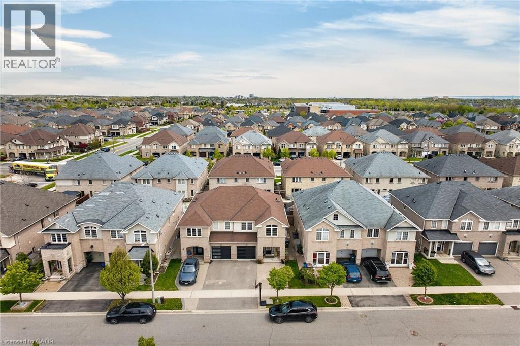 Residential street featuring detached properties with brick and siding exteriors, attached garages, and pitched shingle roofs - 4236 Prudham Avenue, Burlington, ON - Outdoor With View