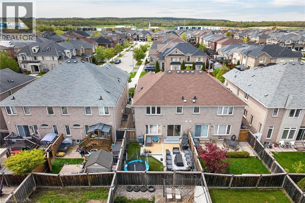 Rear exterior featuring brick facade, private backyard with wooden fencing, and a multi-level deck - 4236 Prudham Avenue, Burlington, ON - Outdoor