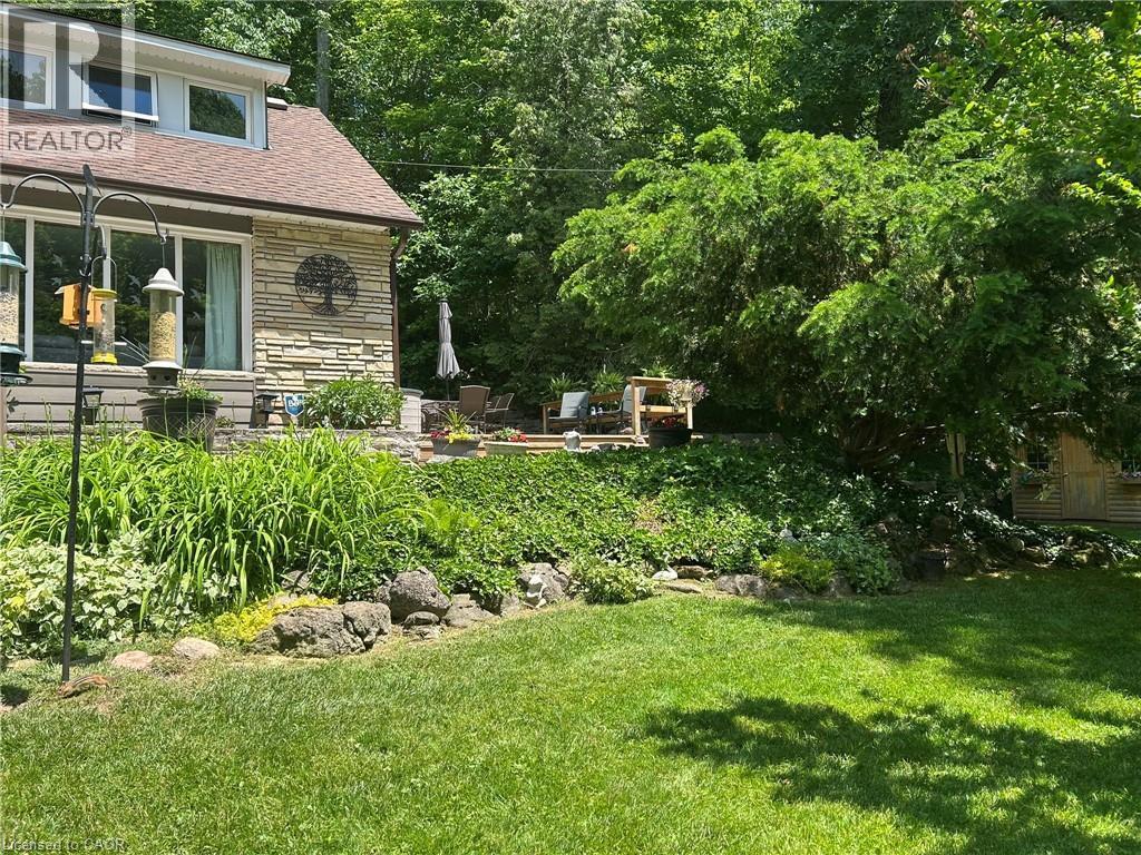 Expansive terraced yard featuring mature landscaping, a stone retaining wall, and a multi-level patio - 1333 Hidden Valley Road, Burlington, ON - Outdoor