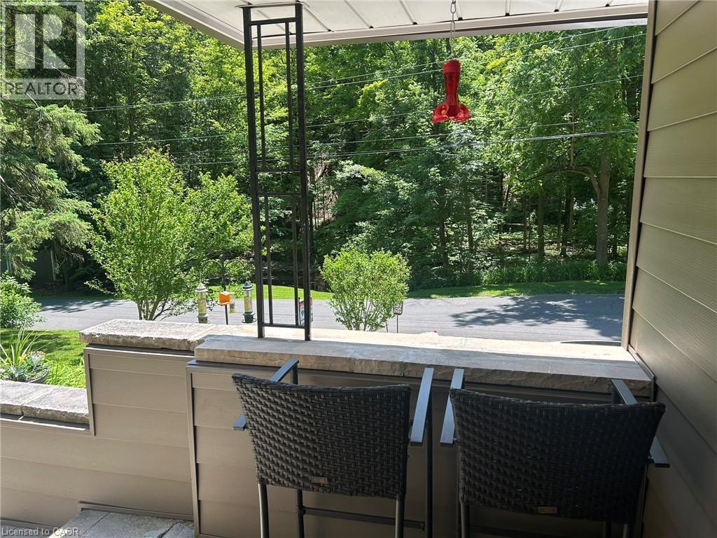 Covered patio featuring a slatted ceiling, decorative metal support column, and a stone-capped half-wall - 1333 Hidden Valley Road, Burlington, ON - Outdoor