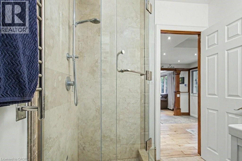 Glass-enclosed shower with stone-look tile surround and a rainfall showerhead - 1333 Hidden Valley Road, Burlington, ON - Indoor Photo Showing Bathroom