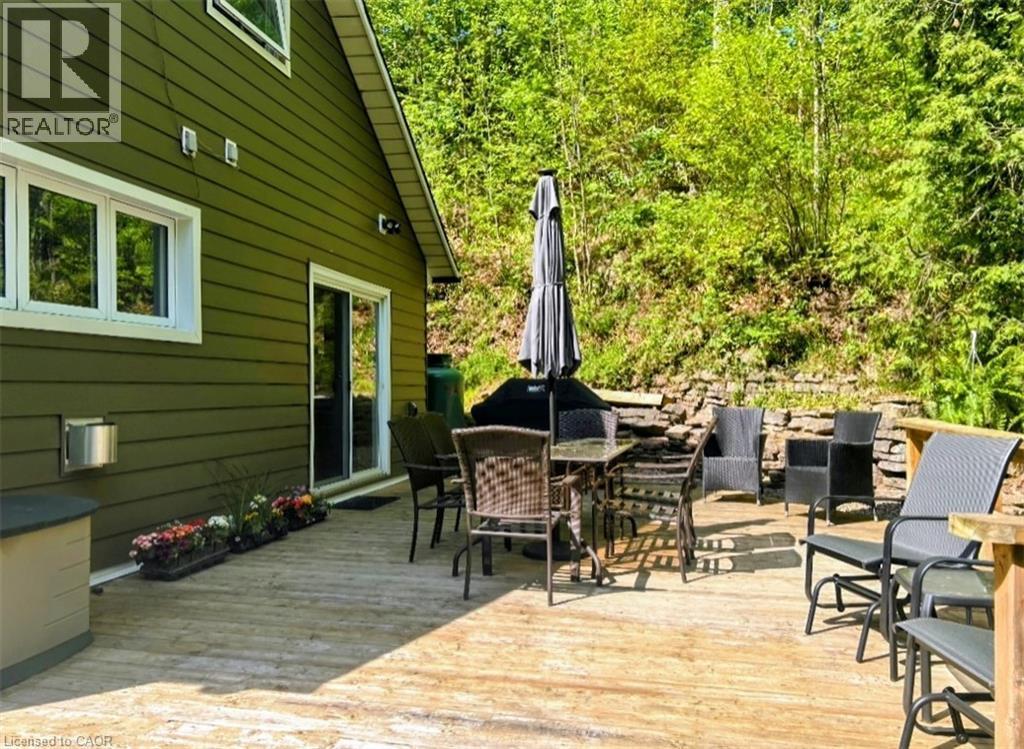 Expansive exterior deck featuring natural wood flooring and a stacked stone retaining wall - 1333 Hidden Valley Road, Burlington, ON - Indoor Photo Showing Dining Room