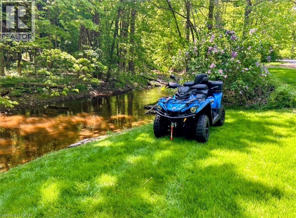 Expansive green lawn bordering a natural waterway with mature trees - 1333 Hidden Valley Road, Burlington, ON - Outdoor