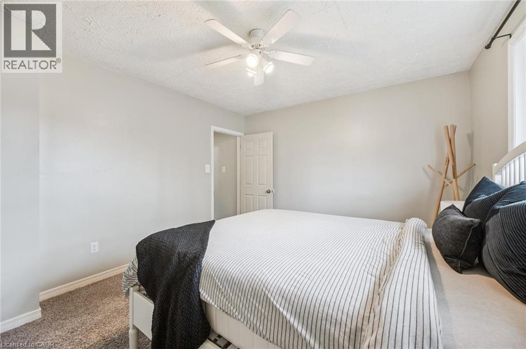 Bedroom featuring neutral wall paint, textured ceiling, a ceiling fan with integrated lighting, window with curtain rod, and carpet flooring - 87 Barbara Crescent, Kitchener, ON - Indoor Photo Showing Bedroom