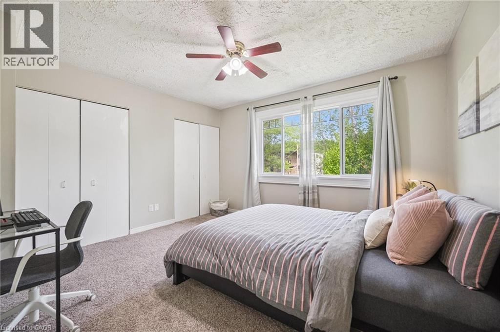 Bedroom featuring multiple bi-fold door closets, a ceiling fan with integrated lighting, and a large window with white trim - 87 Barbara Crescent, Kitchener, ON - Indoor Photo Showing Bedroom