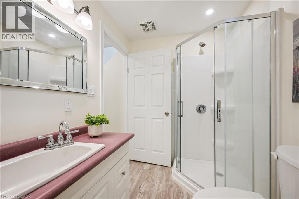 Bathroom featuring a corner glass-enclosed shower, single vanity with a built-in sink, and a framed mirror with overhead lighting - 87 Barbara Crescent, Kitchener, ON - Indoor Photo Showing Bathroom