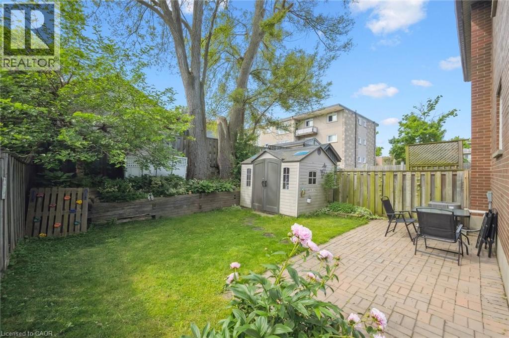 Expansive backyard featuring a brick paver patio, a garden shed, a grassy lawn, and mature trees - 87 Barbara Crescent, Kitchener, ON - Outdoor