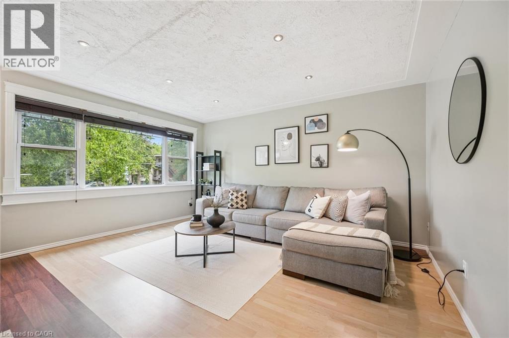 Spacious living area featuring light wood-finish flooring, a tray ceiling with recessed lighting, and a large multi-pane window with white trim - 87 Barbara Crescent, Kitchener, ON - Indoor Photo Showing Living Room