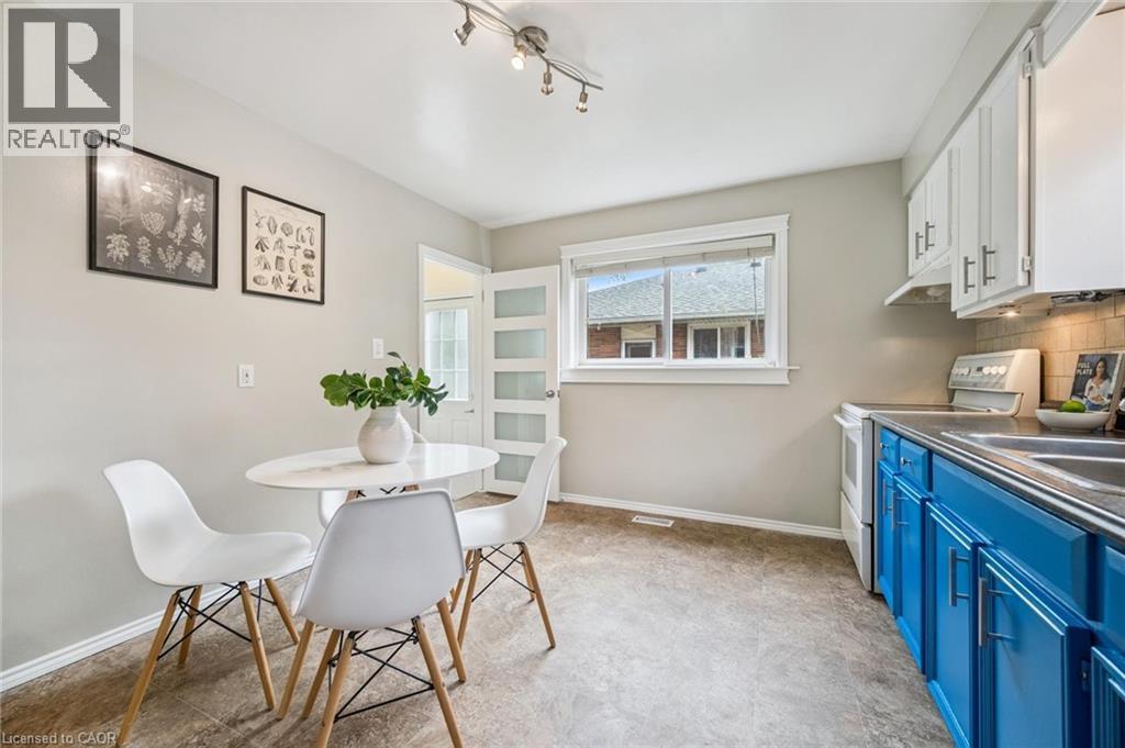 Kitchen area featuring white upper cabinetry, vibrant blue lower cabinetry, a light-toned backsplash, a window, and track lighting - 87 Barbara Crescent, Kitchener, ON - Indoor