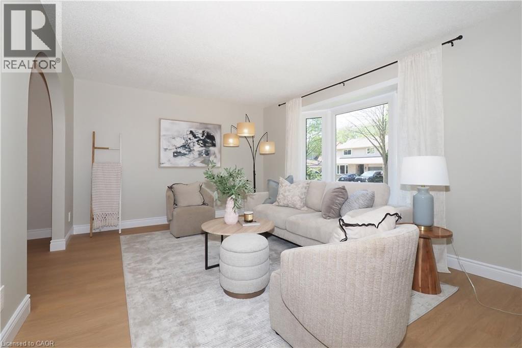Spacious living area featuring light wood-finish flooring, a contemporary area rug, and a large bay window - 27 Scenic Wood Crescent, Kitchener, ON - Indoor Photo Showing Living Room