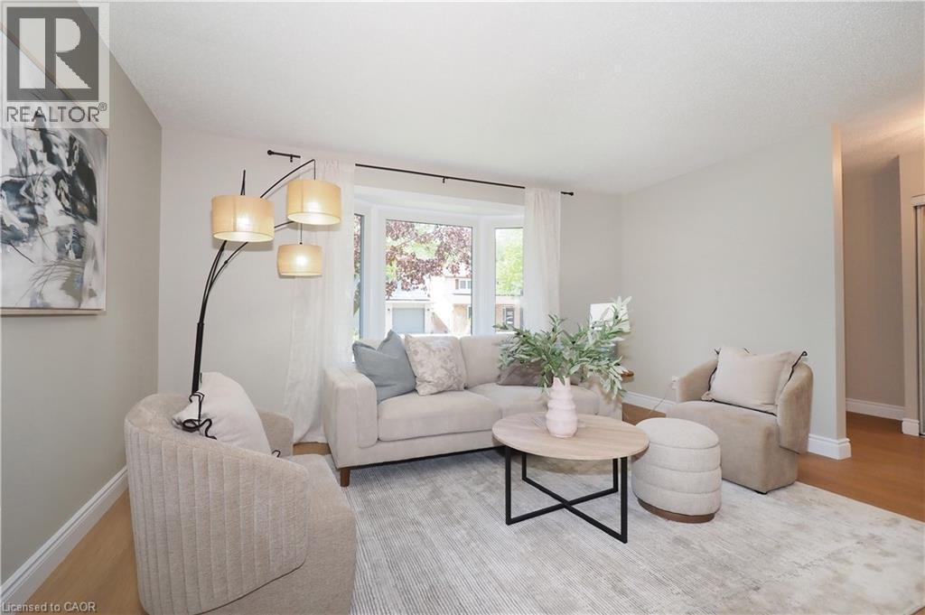 Bright living area featuring a bay window, light wood-finish flooring, and white baseboards - 27 Scenic Wood Crescent, Kitchener, ON - Indoor Photo Showing Living Room