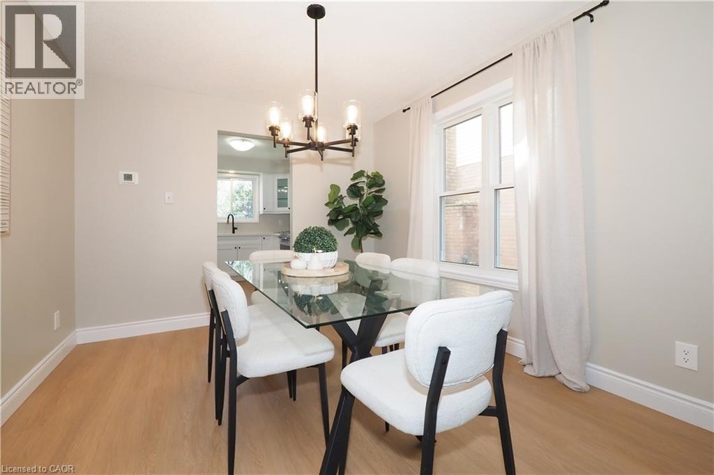 Dining area featuring wood-finish flooring, a contemporary chandelier, and a window with white trim - 27 Scenic Wood Crescent, Kitchener, ON - Indoor Photo Showing Dining Room