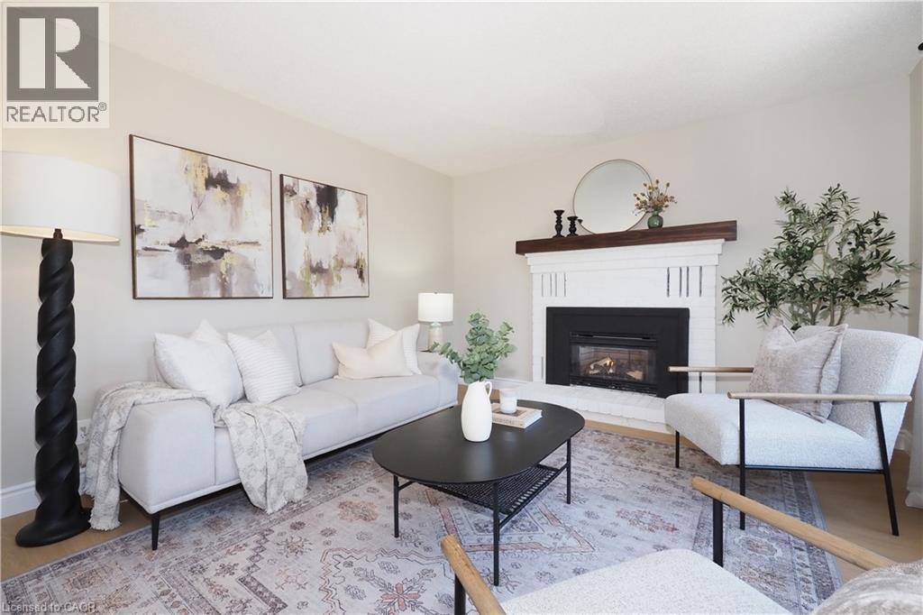 Living area featuring a white brick fireplace with a dark wood mantel, light-toned walls, and wood-finish flooring - 27 Scenic Wood Crescent, Kitchener, ON - Indoor Photo Showing Living Room With Fireplace