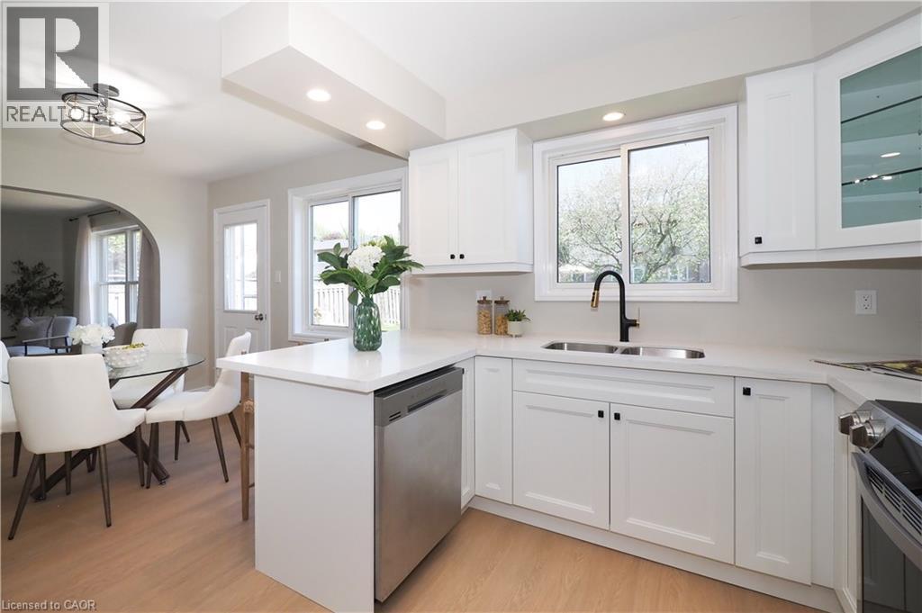 Kitchen featuring white cabinetry, quartz countertops, stainless steel appliances, a black gooseneck faucet, and a dual-basin sink - 27 Scenic Wood Crescent, Kitchener, ON - Indoor