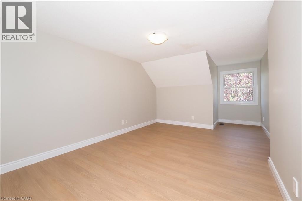 Spacious room featuring light wood-finish flooring, neutral wall paint, a white-framed window, and a flush-mount ceiling light fixture - 27 Scenic Wood Crescent, Kitchener, ON - Indoor Photo Showing Other Room