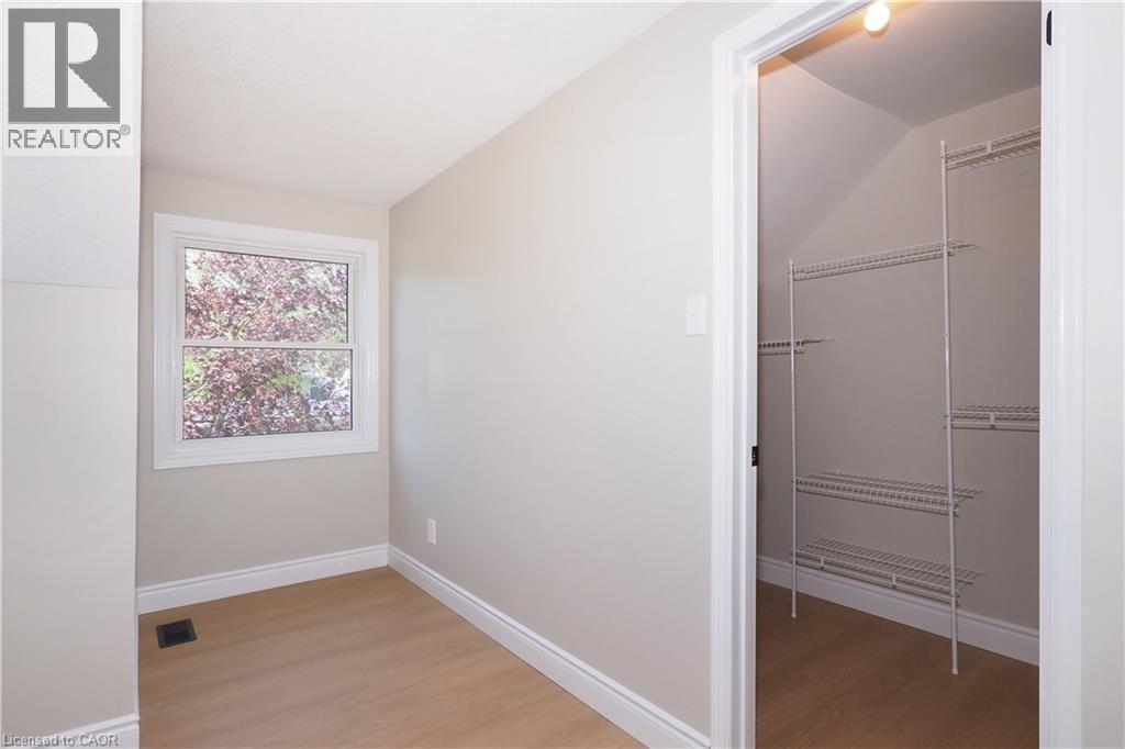 Room featuring wood-finish flooring, a window with exterior foliage, and white baseboards - 27 Scenic Wood Crescent, Kitchener, ON - Indoor Photo Showing Other Room