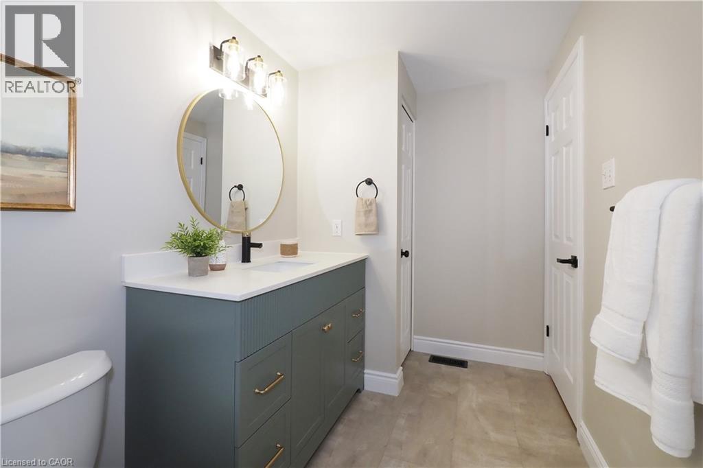 Modern bathroom featuring a deep green vanity with gold-tone hardware, a white countertop, and a round gold-framed mirror - 27 Scenic Wood Crescent, Kitchener, ON - Indoor Photo Showing Bathroom