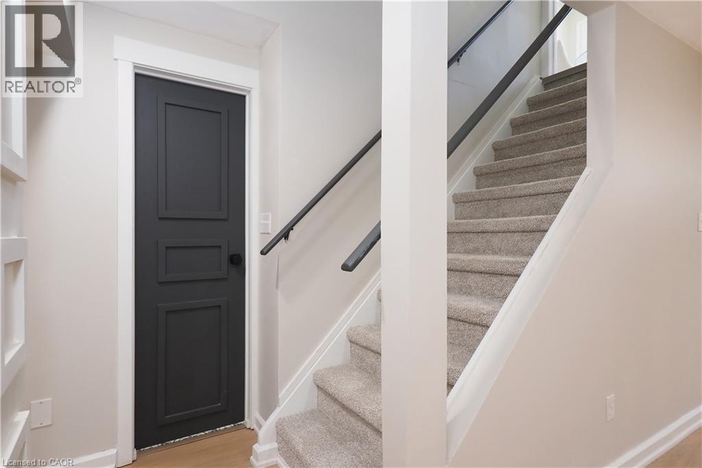 Stairwell featuring carpeted steps and a dark wood-finish handrail, complemented by a paneled door with a dark knob - 27 Scenic Wood Crescent, Kitchener, ON - Indoor Photo Showing Other Room