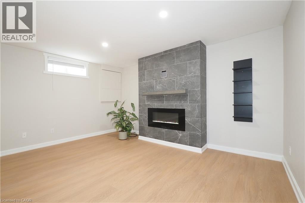 Modern electric fireplace with a stone-look tile surround and wood mantel - 27 Scenic Wood Crescent, Kitchener, ON - Indoor With Fireplace