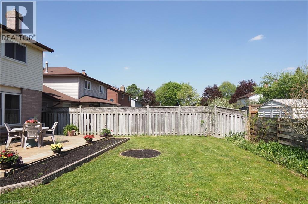 Expansive green lawn with a perimeter wood fence, featuring a raised wood deck - 27 Scenic Wood Crescent, Kitchener, ON - Outdoor