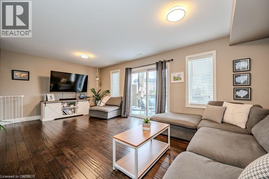 Spacious living area featuring rich wood-finish flooring, recessed lighting, and a sliding glass door providing direct outdoor access - 275 Old Huron Road Unit# 21, Kitchener, ON - Indoor Photo Showing Living Room