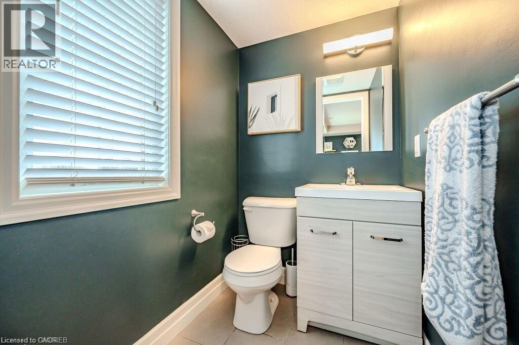 Powder room featuring a single vanity with a white countertop and base cabinet, contemporary mirror, and overhead lighting fixture - 275 Old Huron Road Unit# 21, Kitchener, ON - Indoor Photo Showing Bathroom