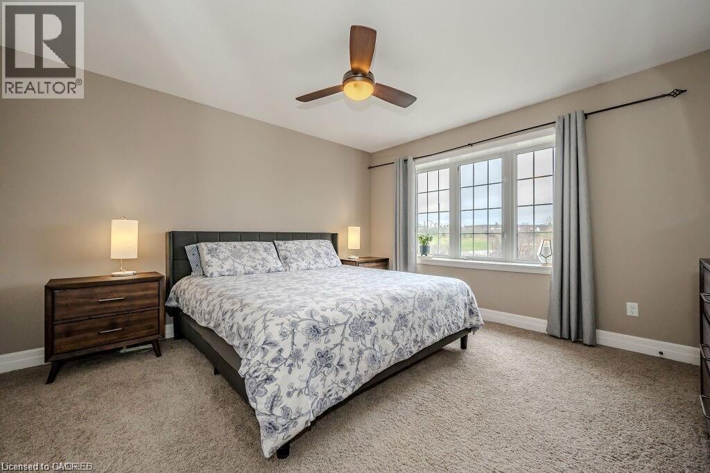 Carpeted room featuring a ceiling fan with integrated lighting, a large window with grid panes, and neutral wall tones - 275 Old Huron Road Unit# 21, Kitchener, ON - Indoor Photo Showing Bedroom