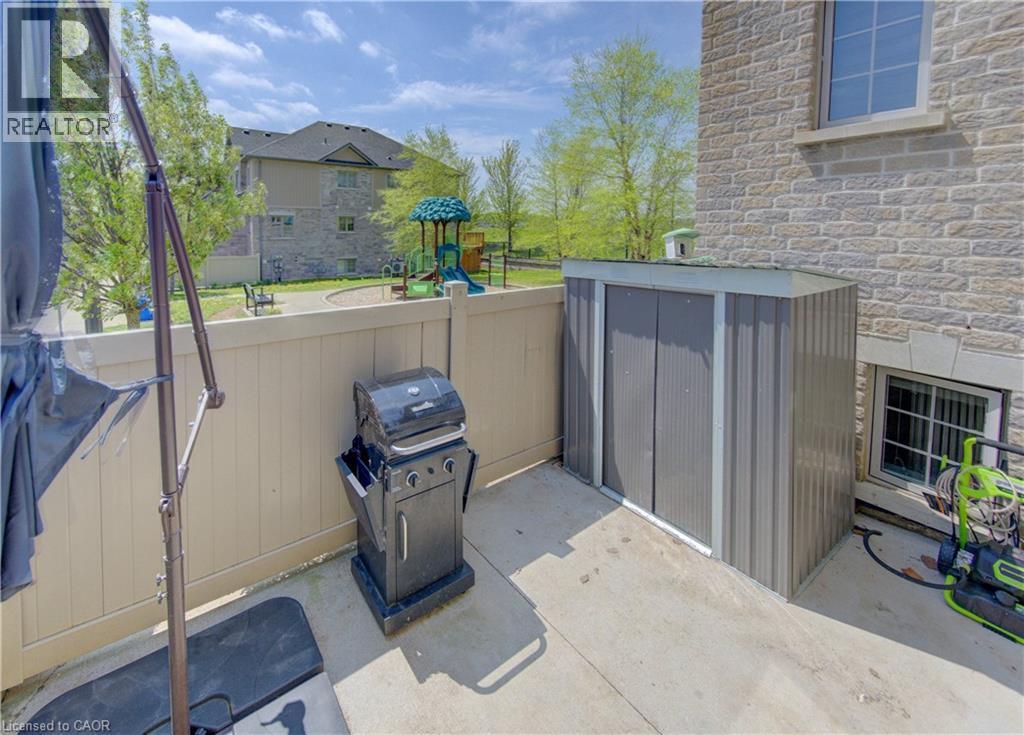 Private concrete patio area featuring a corrugated metal storage shed and a privacy fence - 388 Old Huron Road Unit# 24A, Kitchener, ON - Outdoor With Exterior