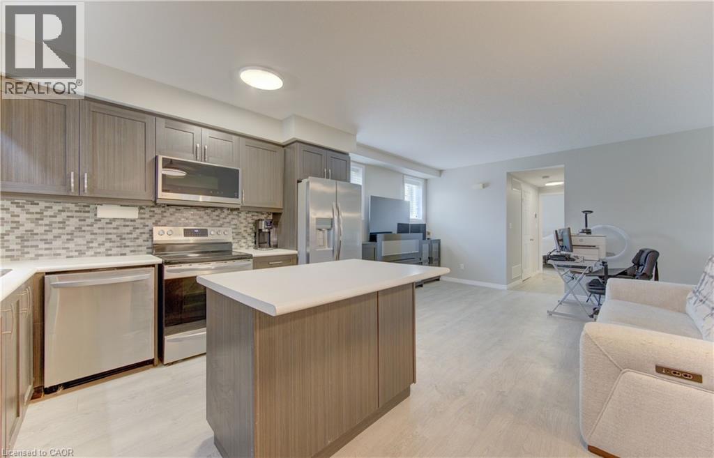Contemporary kitchen featuring stainless steel appliances, grey wood-finish cabinetry, white countertops, and a mosaic tile backsplash - 388 Old Huron Road Unit# 24A, Kitchener, ON - Indoor Photo Showing Kitchen
