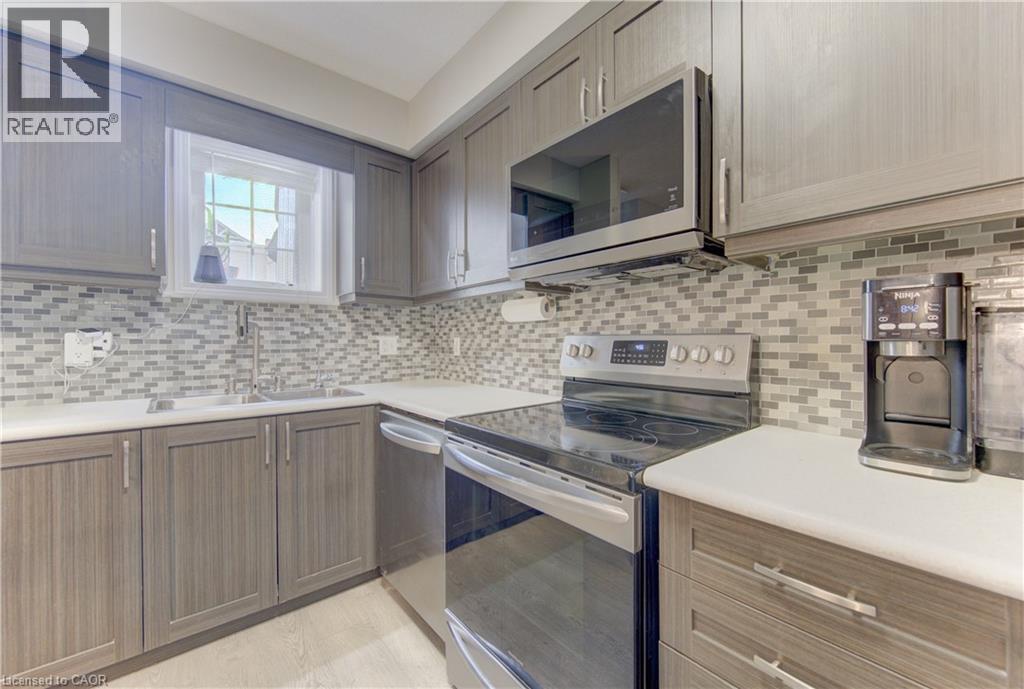Kitchen featuring light wood-finish cabinetry, a mosaic tile backsplash, white countertops, stainless steel appliances, and a double basin sink with a gooseneck faucet - 388 Old Huron Road Unit# 24A, Kitchener, ON - Indoor Photo Showing Kitchen With Upgraded Kitchen