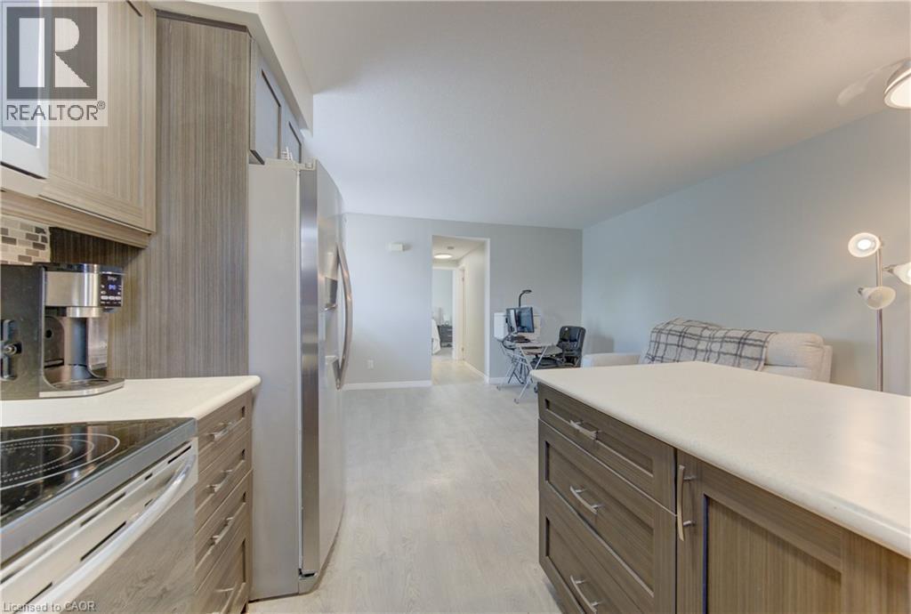 Kitchen featuring wood-finish cabinetry, stainless steel appliances, a light-colored countertop, and a tiled backsplash - 388 Old Huron Road Unit# 24A, Kitchener, ON - Indoor Photo Showing Kitchen