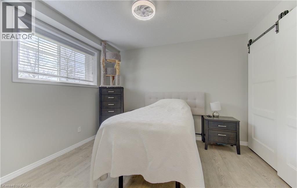 Spacious room featuring light-toned walls, wood-finish flooring, and a large window with blinds - 388 Old Huron Road Unit# 24A, Kitchener, ON - Indoor Photo Showing Bedroom