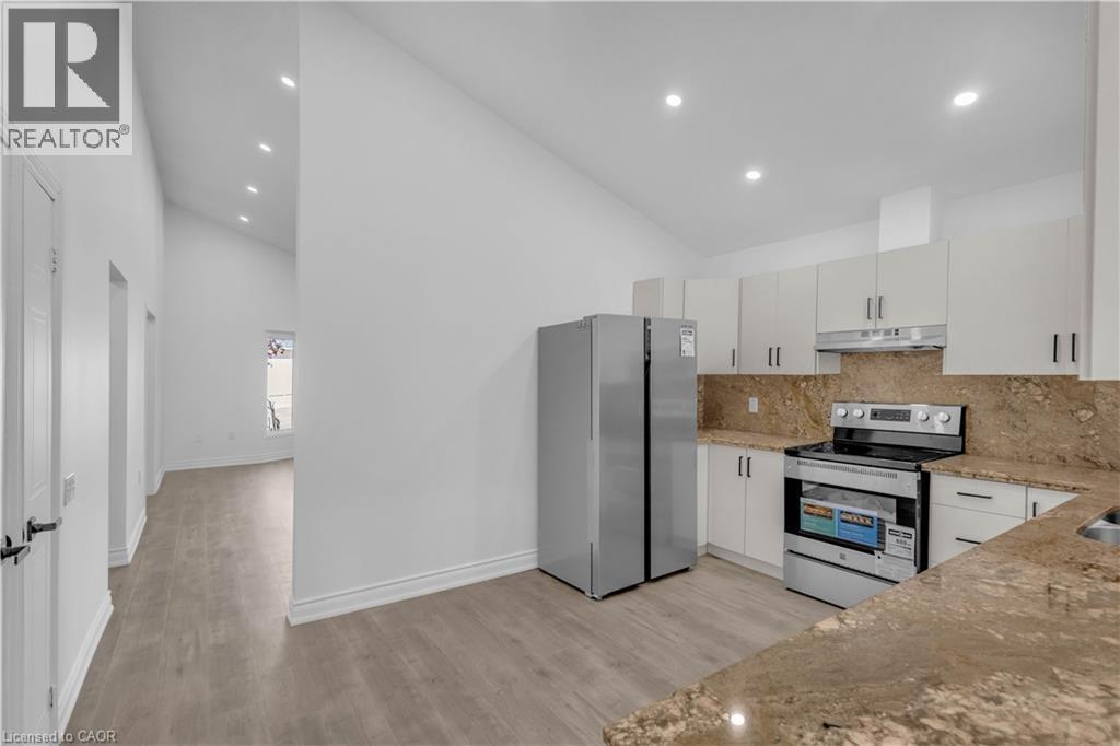 Contemporary kitchen featuring white cabinetry, stainless steel appliances, and stone countertops with a matching backsplash - 375 Silverbirch Boulevard, Hamilton, ON - Indoor Photo Showing Kitchen