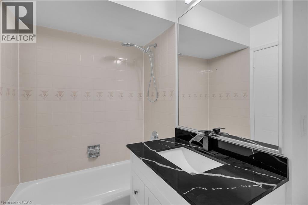 Bathroom vanity with a black countertop and integrated rectangular sink - 375 Silverbirch Boulevard, Hamilton, ON - Indoor Photo Showing Bathroom