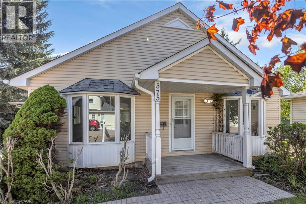 Single-story residence featuring light-colored siding, a covered front porch, and a bay window with a shingled roof - 375 Silverbirch Boulevard, Hamilton, ON - Outdoor