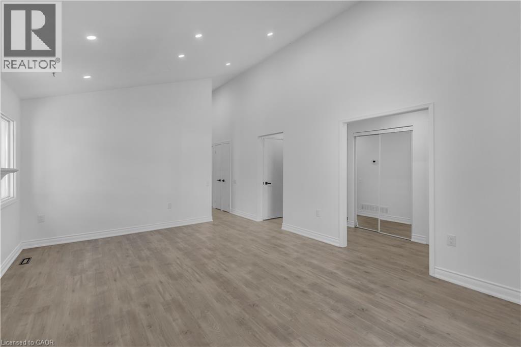 Spacious interior featuring wood-finish flooring, recessed lighting, white walls, and a vaulted ceiling - 375 Silverbirch Boulevard, Hamilton, ON - Indoor Photo Showing Other Room