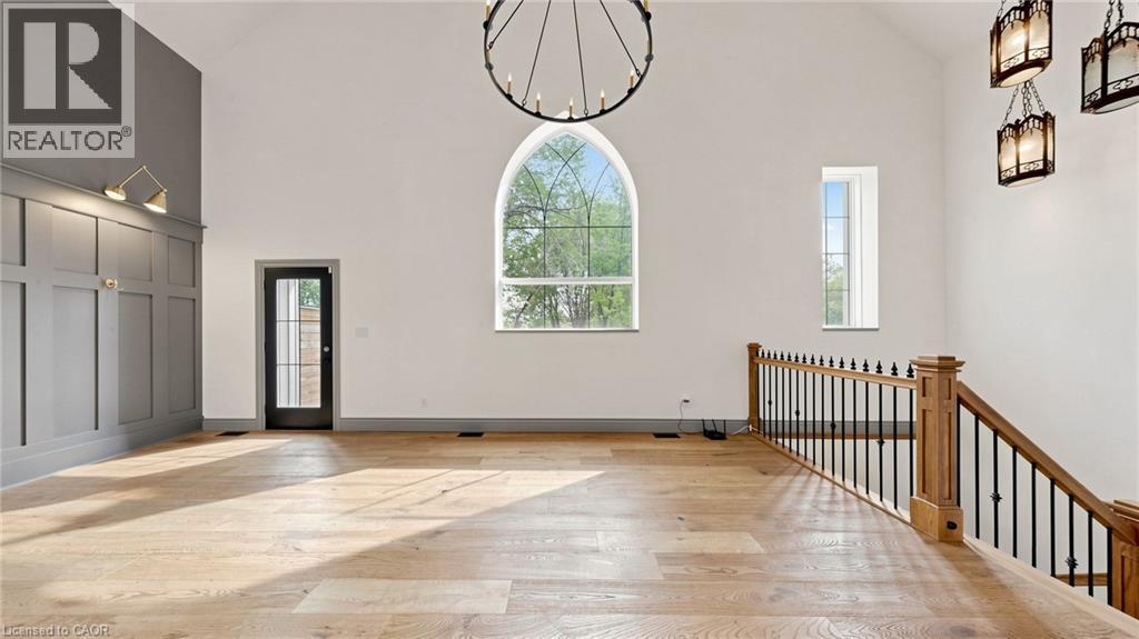 Soaring vaulted ceiling featuring a large arched window and a striking circular chandelier - 41 Talbot Road, Delhi, ON - Indoor Photo Showing Other Room