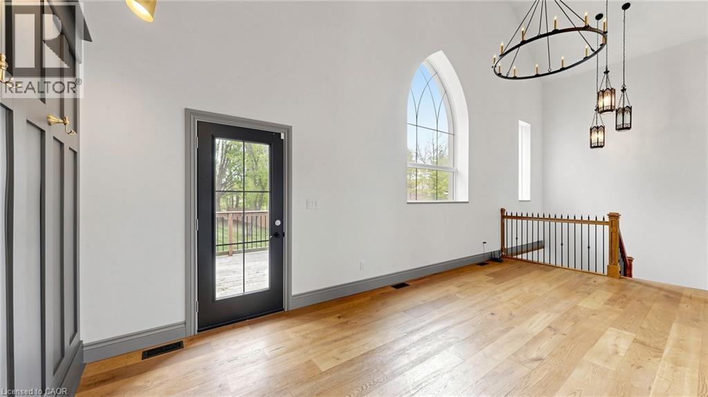 Spacious room featuring vaulted ceilings, light wood-finish flooring, and a large arched window - 41 Talbot Road, Delhi, ON - Indoor Photo Showing Other Room